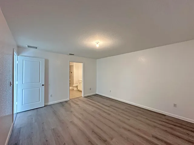 a view of an empty room with wooden floor and closet