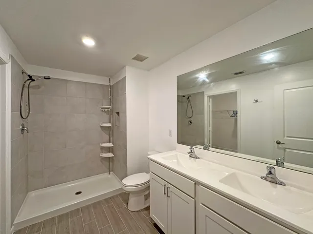 a bathroom with a shower sink vanity mirror and toilet