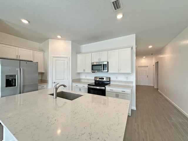 a kitchen with granite countertop a refrigerator stove and sink