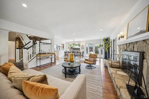 a dining room with wooden floor a chandelier a glass table and chairs