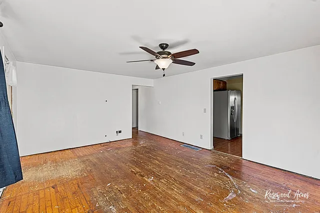 an empty room with a ceiling fan and wooden floor