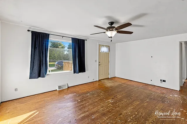 a view of an empty room with a window and a ceiling fan