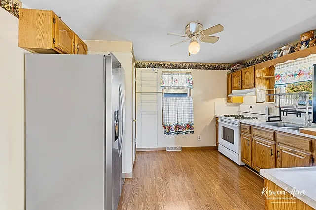 a kitchen with stainless steel appliances a stove a refrigerator a sink a dining table and chairs with wooden floor