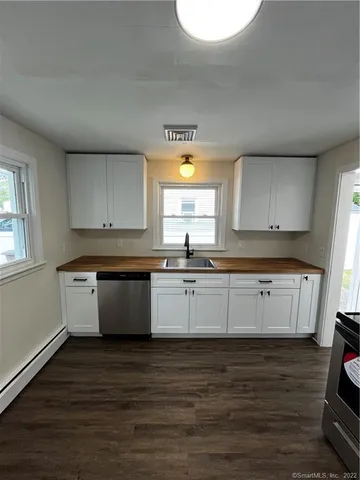 a kitchen with granite countertop white cabinets and wooden floor