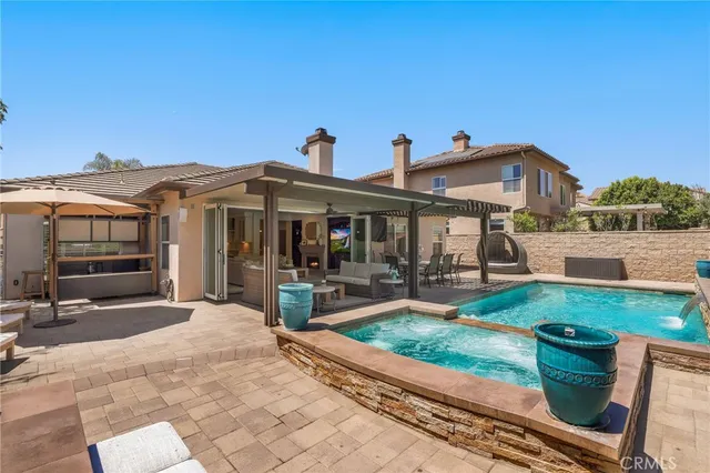 a view of a patio with a table and chairs under an umbrella with a barbeque grill and plants