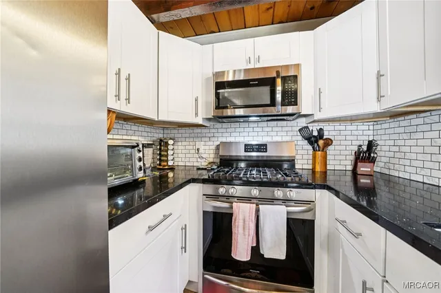 a kitchen with stainless steel appliances granite countertop white cabinets stove top oven and sink