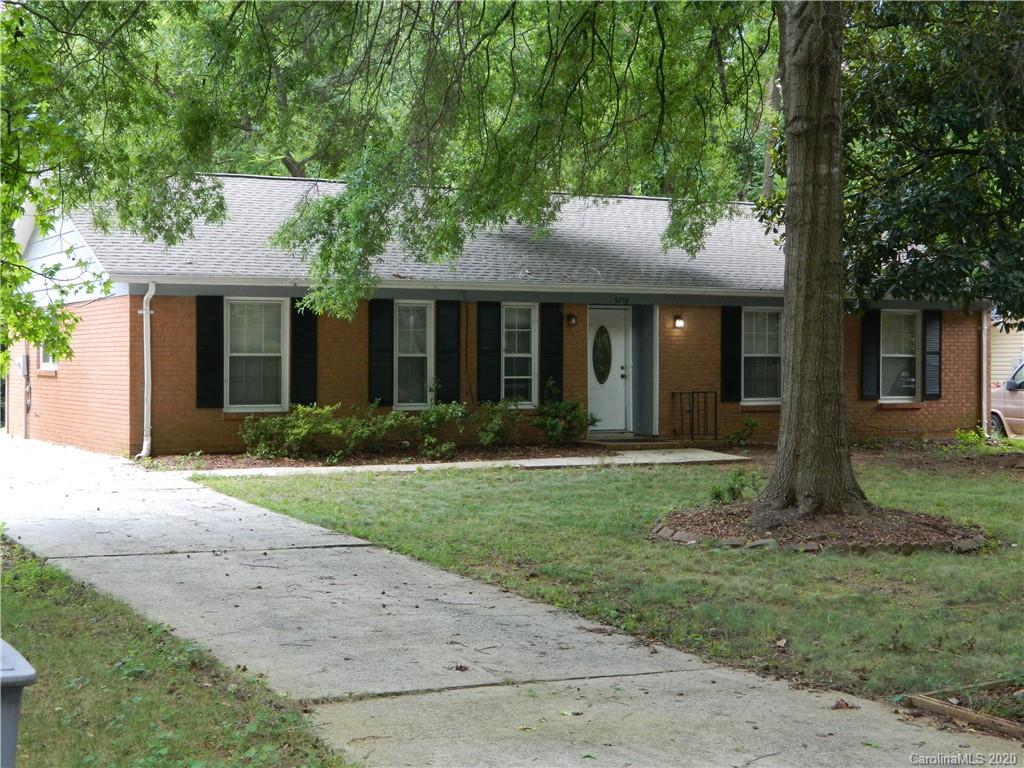a view of a brick house with a yard and large tree