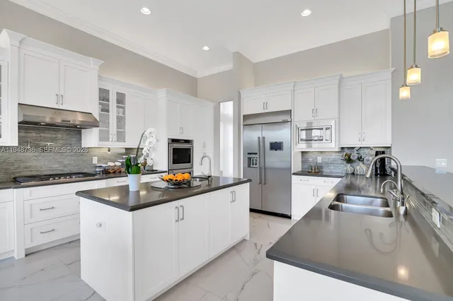 a kitchen with kitchen island granite countertop a sink counter top space appliances and cabinets