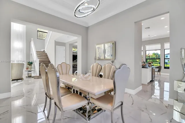 a dining table kitchen island with stainless steel appliances kitchen island granite countertop a refrigerator a stove a sink and a dining table with wooden floor