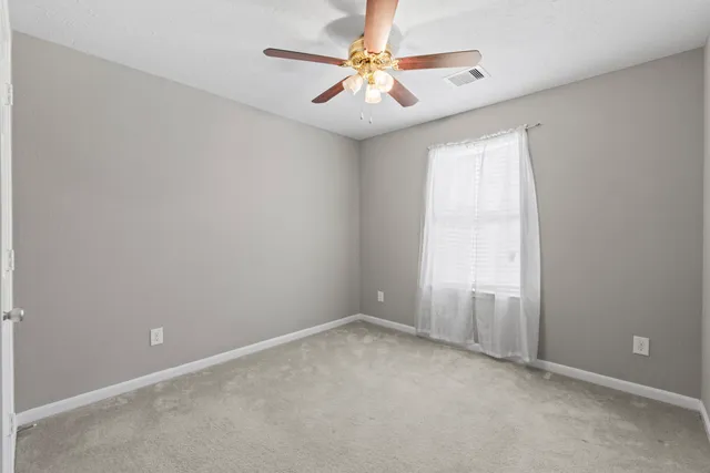 an empty room with windows and fan