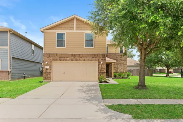 a front view of a house with a yard and trees