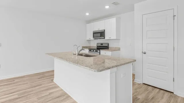 a view of a hallway with wooden floor and a bathroom