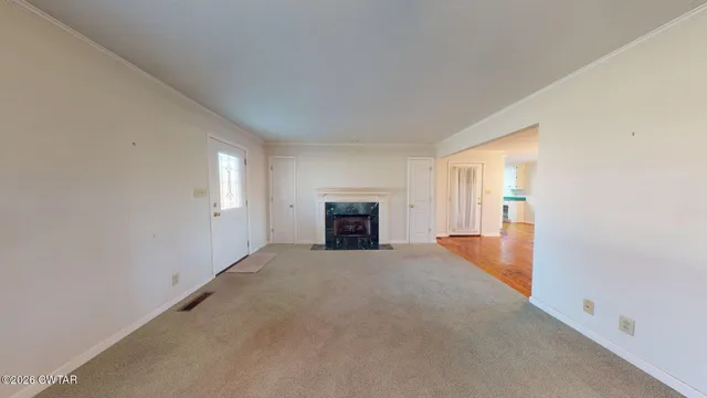an empty room with windows and fireplace