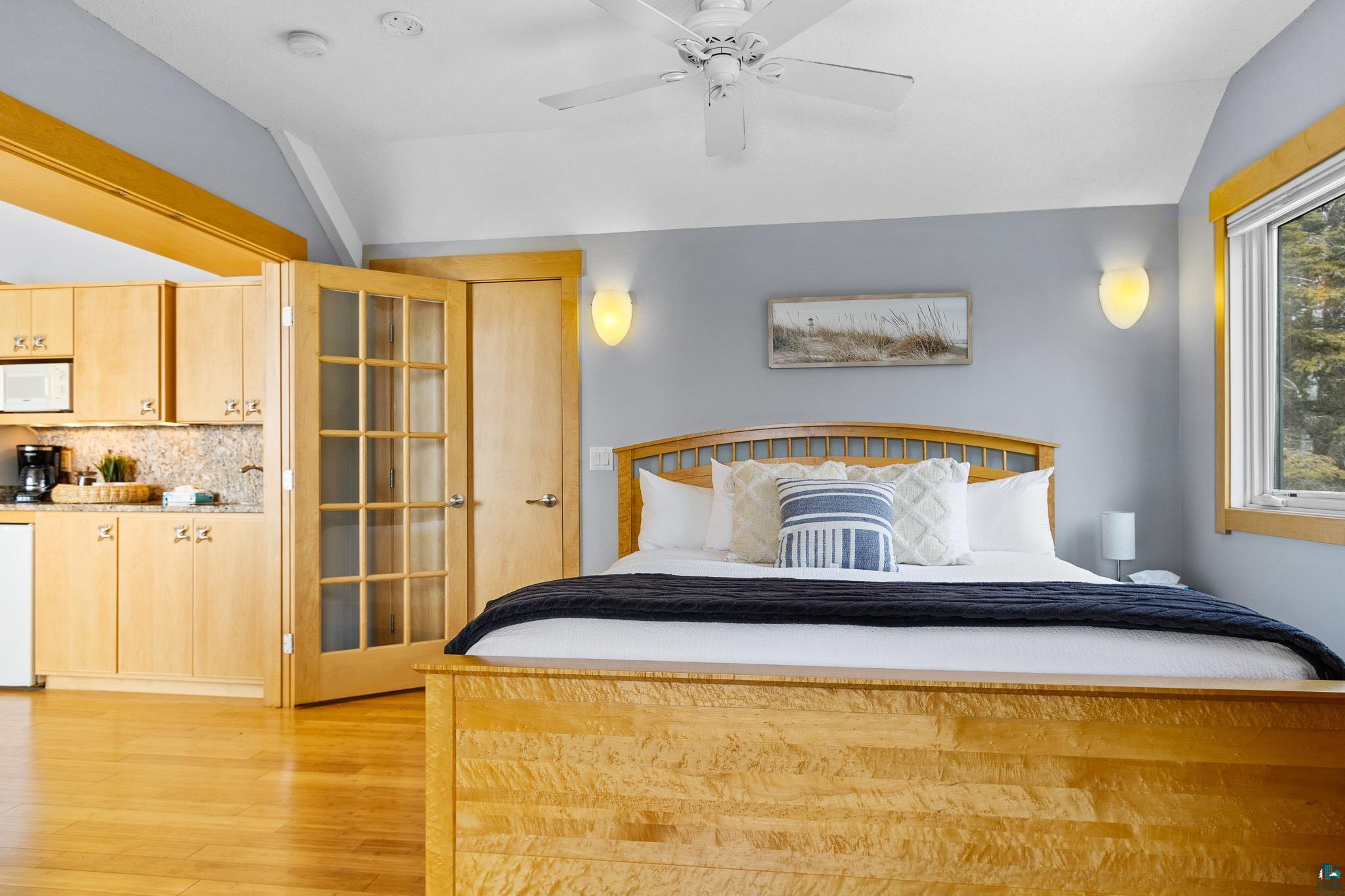 5163 Greenwood Road Duluth, MN 55804 - Photo 25 of 47 Vaulted ceiling with a ceiling fan, light wood-finish flooring, a kitchenette with wood cabinetry and a speckled countertop, and glass-paneled French doors