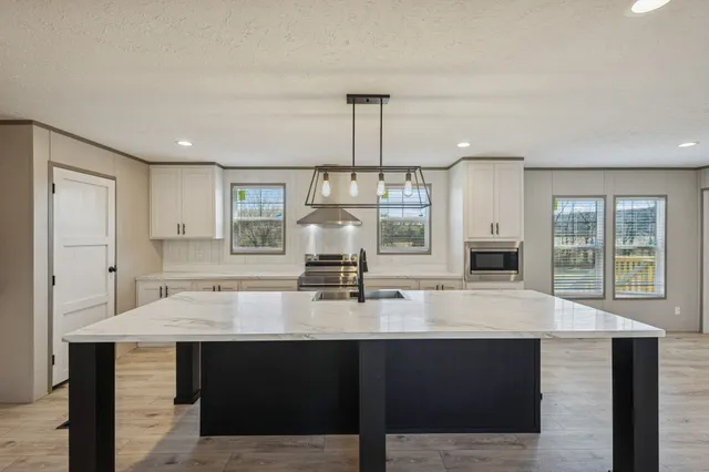 a large kitchen with stainless steel appliances a large counter top a stove a chimney a sink and a refrigerator