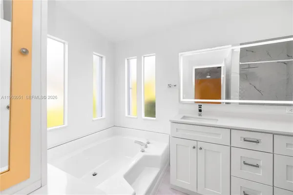 a bathroom with a tub sink and mirror