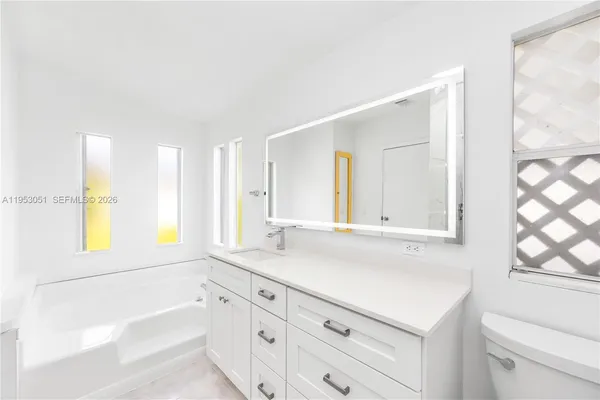 a bathroom with a granite countertop sink mirror and a bathtub