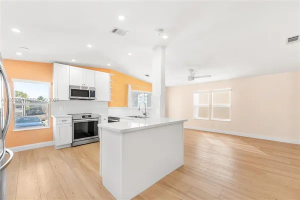 a kitchen with stainless steel appliances a stove top oven a sink a refrigerator a center island and cabinets