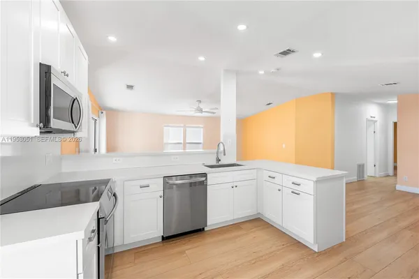 a kitchen with a sink a stove a refrigerator and white cabinets