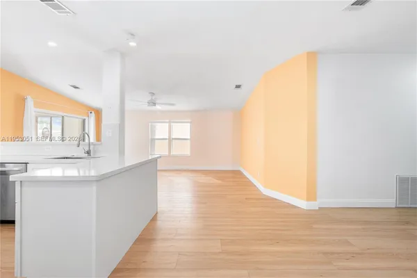a view of a kitchen with kitchen island a sink wooden floor and a living room