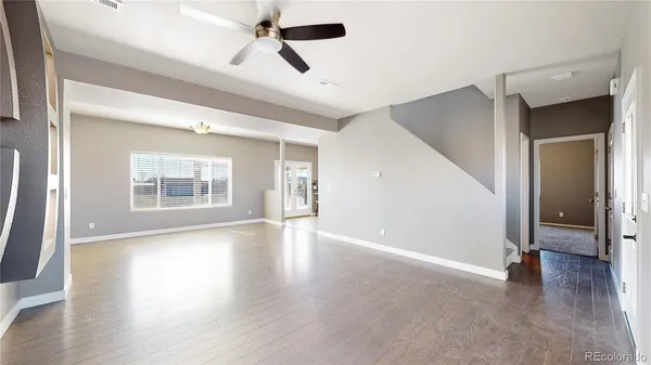 a view of an empty room with a window and wooden floor