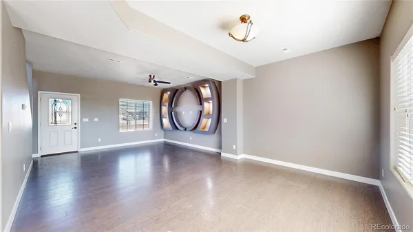 an empty room with wooden floor mirror and windows