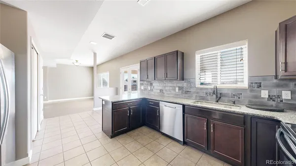 a large kitchen with granite countertop a sink dishwasher stove and cabinets