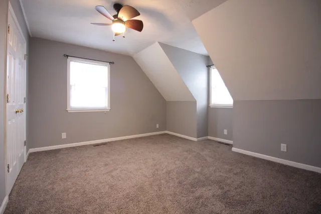 an empty room with ceiling fan and windows