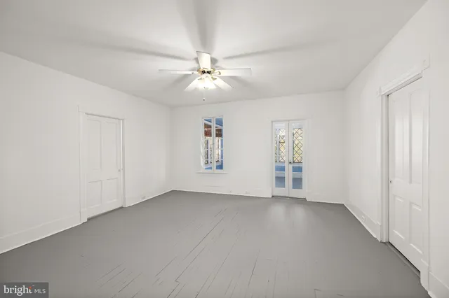 an empty room with fan and windows