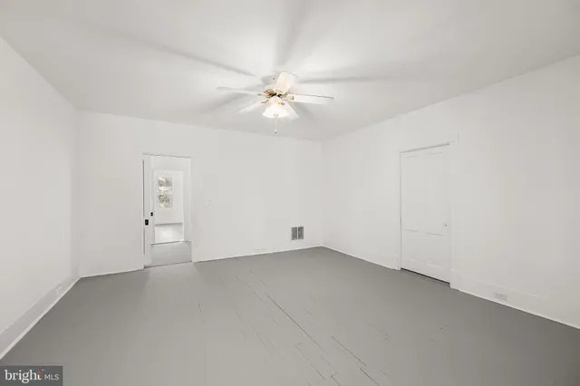 an empty room with a ceiling fan and a fan
