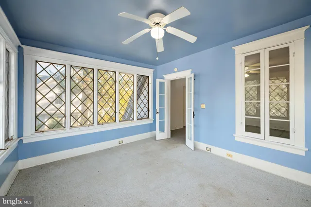 an empty room with chandelier fan and windows