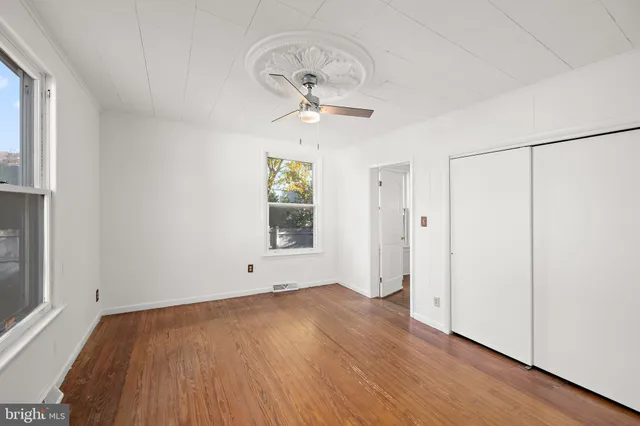 a view of empty room with wooden floor and fan