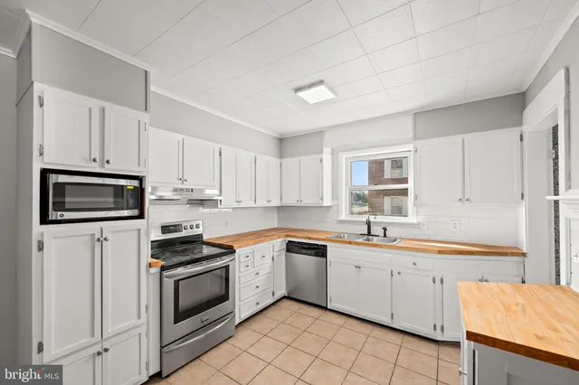 a kitchen with a sink white cabinets and white appliances