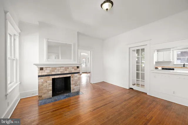 an empty room with wooden floor and a fireplace