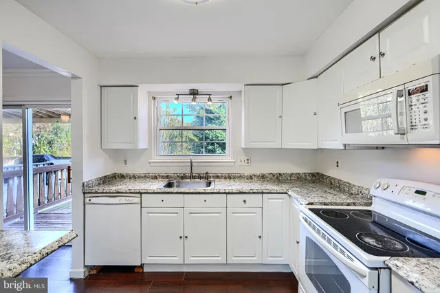 a kitchen with granite countertop cabinets stainless steel appliances a sink and a window