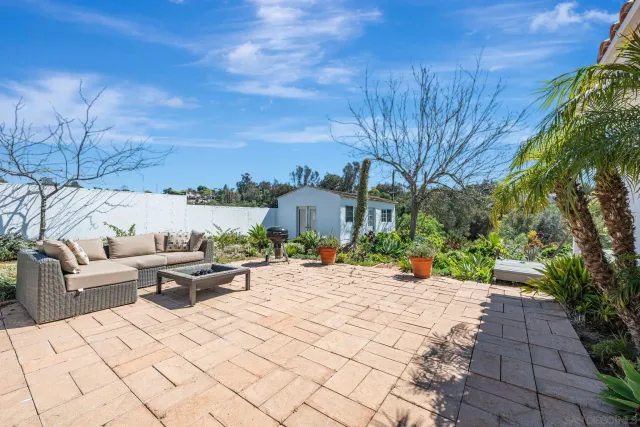 a view of a patio with table and chairs potted plants and large tree