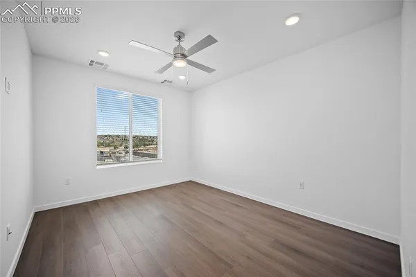 an empty room with wooden floor fan and windows