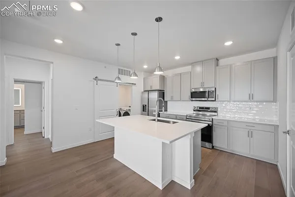 a kitchen with kitchen island a sink a stove a refrigerator and white cabinets