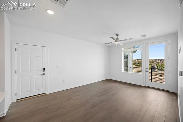 an empty room with wooden floor and windows