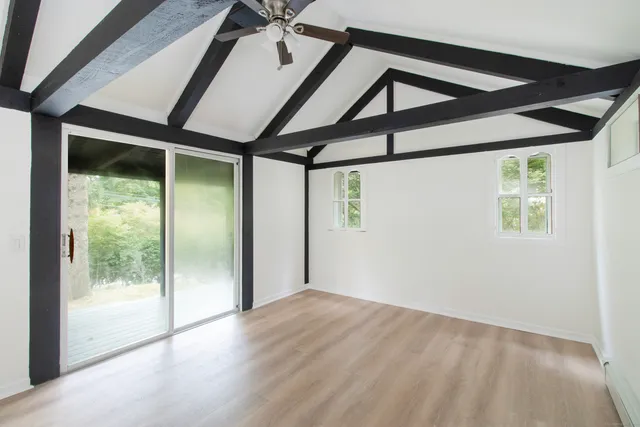 a view of empty room with wooden floor and fan