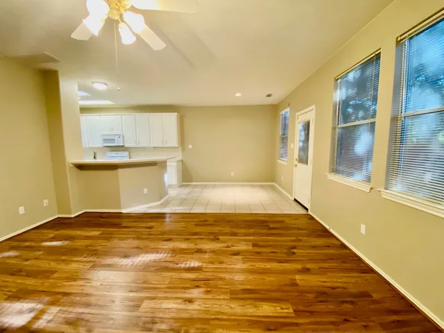 a view of a kitchen with kitchen island a sink wooden floor and a large window