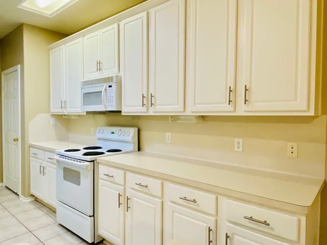 a kitchen with white cabinets and white appliances