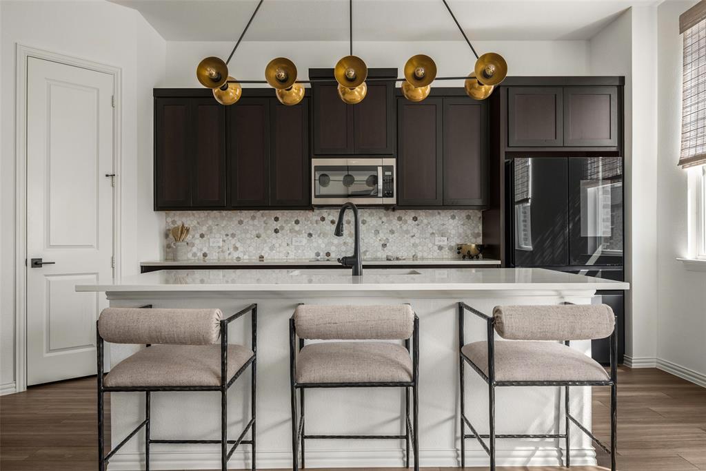 7537 Laburnam Road Dallas, TX 75228 - Photo 1 of 30 Kitchen featuring dark wood-finish cabinetry, a stone mosaic tile backsplash, built-in microwave, and a black refrigerator