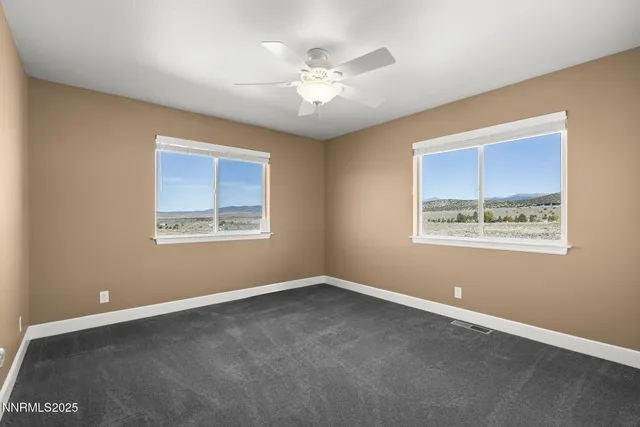 an empty room with windows and ceiling fan