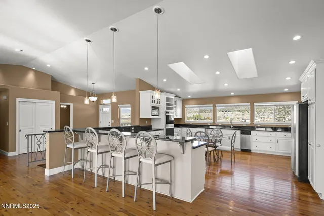 a room with lots of white furniture and view of kitchen