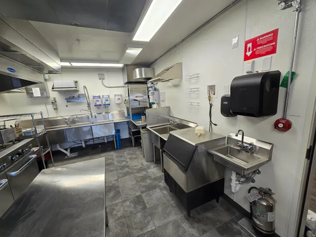 a living room with stainless steel appliances furniture a rug and a kitchen view