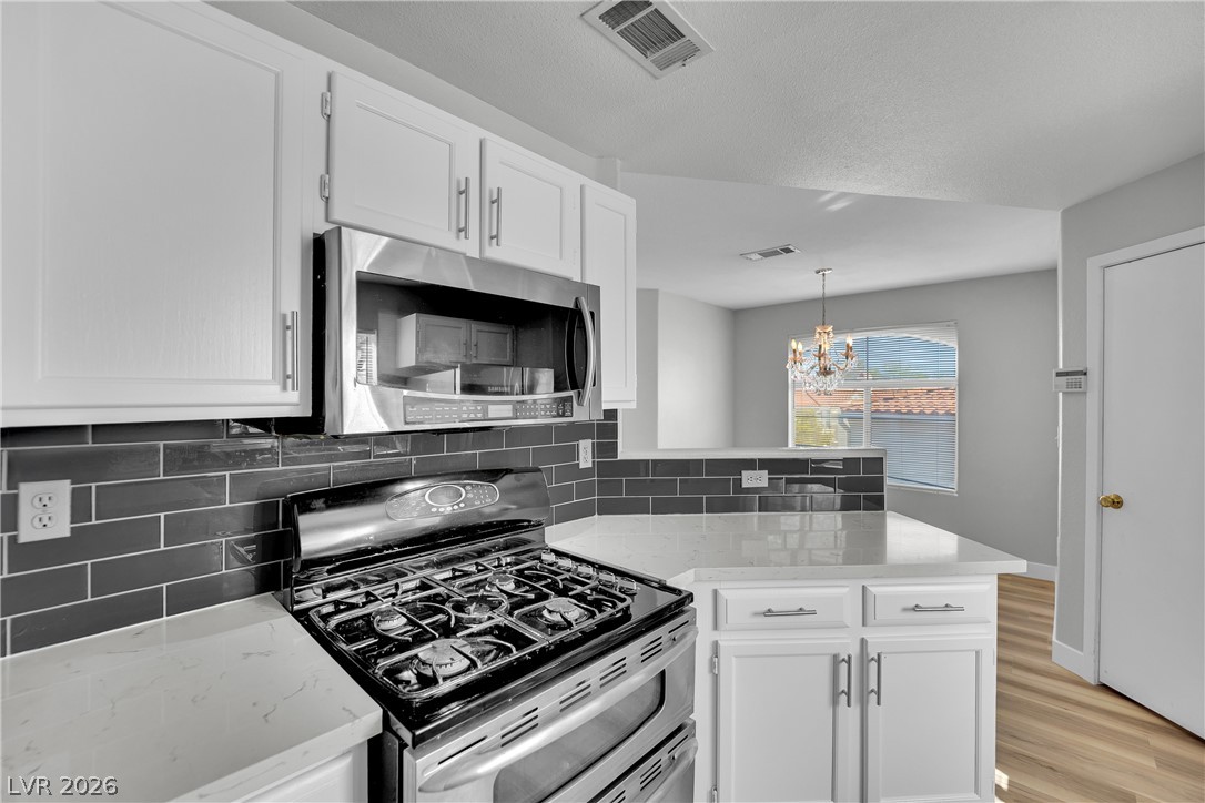 698 South Racetrack Road, Unit 1521 Henderson, NV 89015 - Photo 10 of 33 Modern kitchen features a gas range, microwave, sleek countertops, and crisp cabinetry, creating a stylish culinary space.