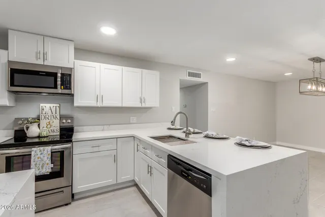 a kitchen with a sink dishwasher stove and white cabinets
