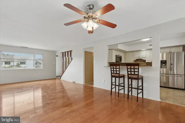 a view of a livingroom with furniture wooden floor a ceiling fan and a kitchen
