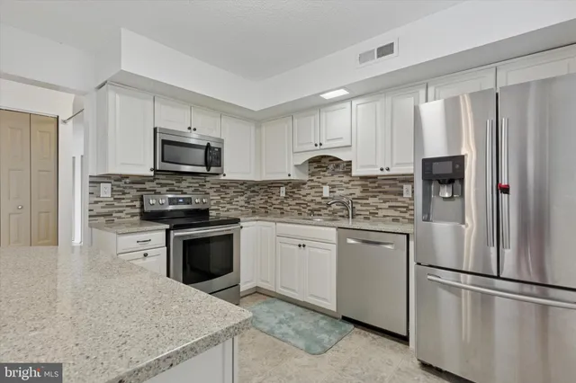 a kitchen with stainless steel appliances granite countertop a refrigerator stove microwave and sink